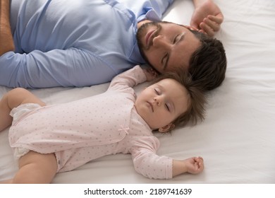 Tired young father falls asleep near newborn baby girl, close up above shot. Sweet infant daughter sleep in bed with loving daddy enjoy daytime nap at home. Fatherhood, family, infancy, rest concept - Shutterstock ID 2189741639