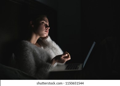 Tired Tired Young Girl Sitting In A Bed In The Evening, Watching A Boring Movie On Her Laptop