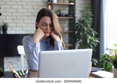 Tired young girl student sitting at table, leaning head on hand, napping during break pause time at home. - Shutterstock ID 1859449681