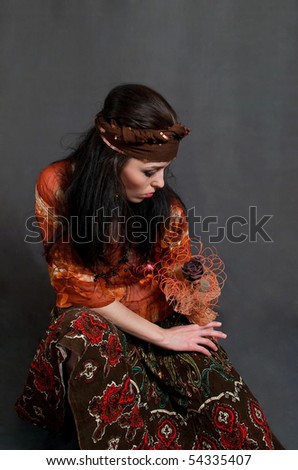 tired young Gypsy woman on the gray background