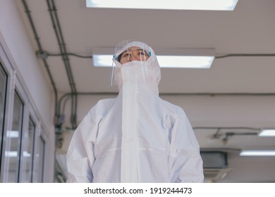 Tired Young Healthcare Worker Wearing PPE Suit With Protective Face Shield And Mask Working In Hospital During Covid-19 Pandemic