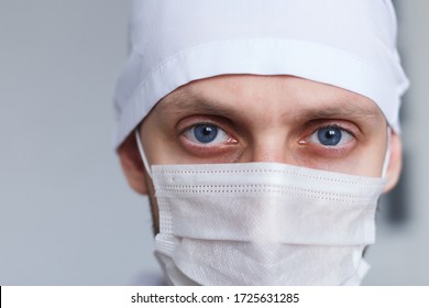 Tired Young Man Doctor In Mask During Coronavirus. Dramatic Portrait Of Medic, Close-up