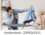 Tired young man ironing clothes in laundry room