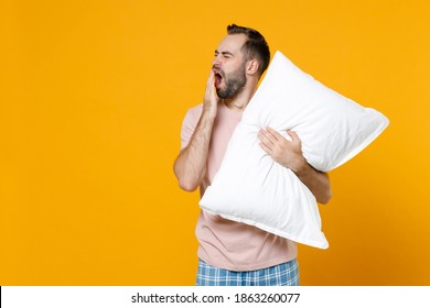 Tired Young Man In Pajamas Home Wear Hold Pillow Did Not Get Enough Sleep Last Night And Barely Got Up In The Morning Yawning Resting At Home Isolated On Yellow Background. Relax Good Mood Concept