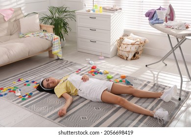 Tired Young Mother Sleeping On Floor In Messy Living Room