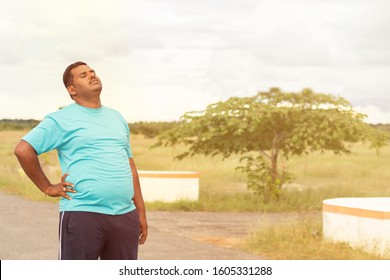 Tired Young Obese Man Holiding His Back While Jogging - Concept Of Fat Man Fitness And Unhealthy Lifestyle.