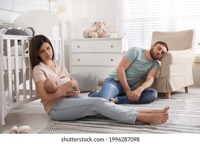 Tired Young Parents With Their Baby Sleeping On Floor In Children's Room