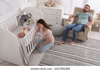Tired young parents and their baby sleeping in children's room