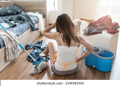 Tired young woman in the bedroom with cleaning products and equipment, Housework concept
