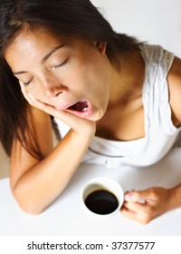 Tired Young Woman Drinking Coffee In Early Morning, Yawning And Very Tired.