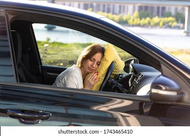 Tired Young Woman Driver Asleep On Pillow On Steering Wheel, Resting After Long Hours Driving A Car. Fatigue. Sleep Deprivation. 