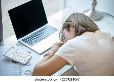 tired young woman falling asleep at work desk with laptop and document, overworked unmotivated businesswoman.
