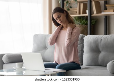 Tired Young Woman Touch Stiff Neck Feeling Hurt Joint Back Pain Rubbing Massaging Tensed Muscles Suffer From Fibromyalgia Ache After Long Computer Work Study In Incorrect Posture Sit On Sofa At Home 