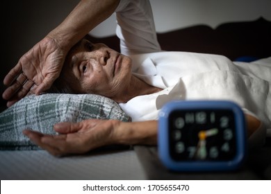 Tired,exhausted asian senior woman suffering from insomnia for months,chronic insomnia,unable to sleep at night,elderly people with hand on forehead and open eyes,lying on bed at home,lack of sleep - Shutterstock ID 1705655470