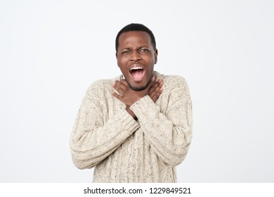 Tiredness of relationship concept. Portrait of upset funny african american man in sweatert, holding hands on neck while choking