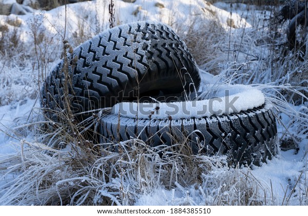 The tires from the car lie on the street covered\
with snow