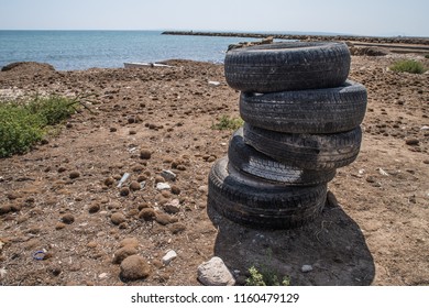 tires stacked and abandoned on the beach - Powered by Shutterstock