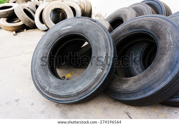 Tires stacked\
near cement wall, used car\
tires
