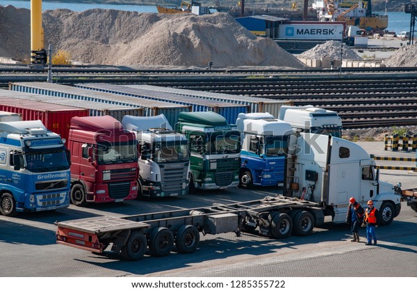 TIS cargo\
terminal in largest dry cargo port of Ukraine. Industrial landscape\
with row of container trucks and two workers in orange safety\
helmets. Odessa, Ukraine, 10 12\
2018
