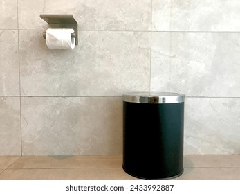 tissue roll and trash can in the bathroom with a marble wall background, items needed for comfort in the bathroom