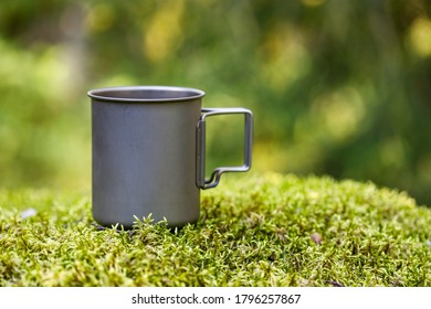 Titanium Mug On Green Moss In Forest Background Blurred