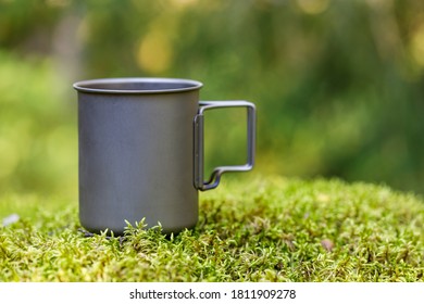 Titanium Mug On Green Moss In Forest Background Blurred