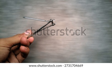 Titanium Nail Clipper Held in Hand with Motion Blur on Gray Background