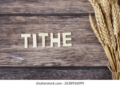 Tithe text with ripe wheat on wooden background. Top view. Generosity, Christian giving, offering, and faith in God Jesus Christ, biblical concept.