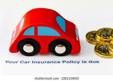 Title Of Insurance Letter For Renewal Of Car Insurance With Wooden Car And One Pound Coins On A Plain White Background. Cost Of Living Concept. No People.