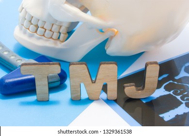 TMJ medical abbreviation of temporomandibular joint. TMJ letters surrounded by human skull with lower jaw, neurological hammer and radiographs. Concept of anatomy, pathology of temporomandibular joint