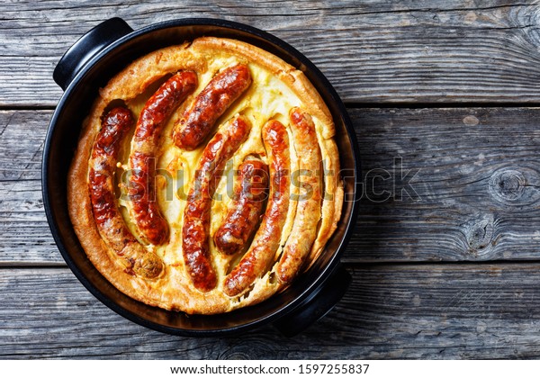Toad in the hole, Sausage Toad, traditional\
English dish consisting of sausages in Yorkshire pudding batter,\
horizontal view from above,\
flatlay