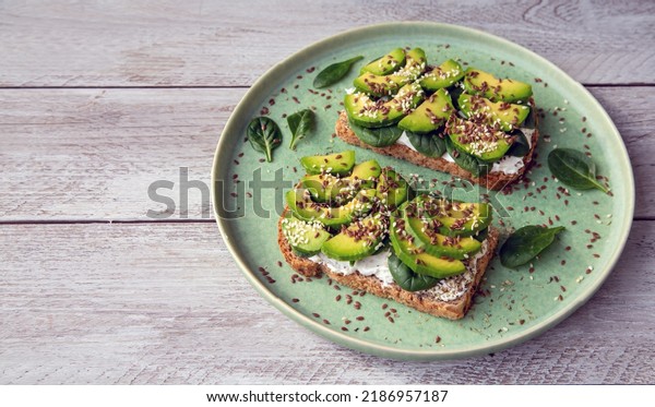 Toast with avocado, cottage cheese,\
spinach, sesame seeds, flax seeds. Healthy food rich in fiber,\
trace elements, omega acids, unsaturated\
lipids.