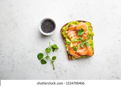 Toast with avocado cream and smoked salmon over white background, top view