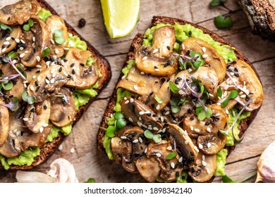 Toast avocado, mushrooms and microgreen whole grain sandwich. Decorated with sesame. Vegetarian food. Vegan menu. Food recipe background. Close up.