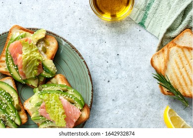 Toast with avocado and salmon fish on the table close-up.