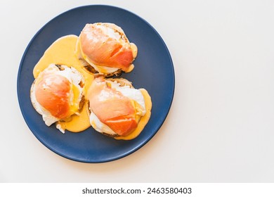 Toast with eggs benedict, salmon and hollandaise sauce on a blue plate on a white background. Space for text. High quality photo - Powered by Shutterstock