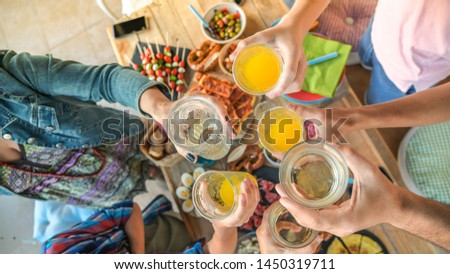 Toast with friend dinner on the terrace enjoying together. Summer aperitif with group of friends. Joy and festivities in family View from the top of a table with many foods and glass in hands cheer up