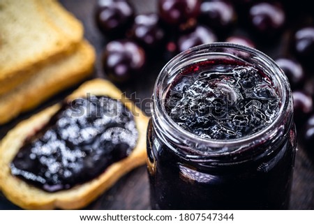 toast with grape jam, on rustic wooden table. Jabuticaba, exotic Brazilian fruit, used in cooking, as a sweet.