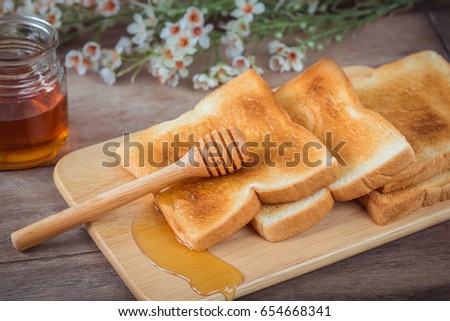 Toast with honey on wooden plate