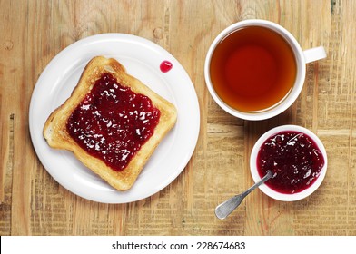 Toast With Jam And Cup Of Tea On Old Wooden Table. Top View