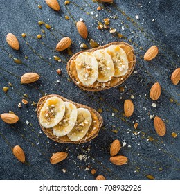 Toast With Peanut Butter, Banana And Almond Nuts On Dark Table. Diet Natural Breakfast. Flat Lay, Top View