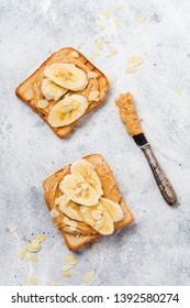 Toast With Peanut Butter, Banana Slices, Honey And Almond Flakes On Old Gray Concrete Background. Top View.