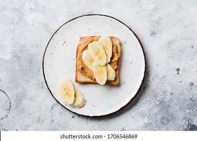 Toast With Peanut Butter, Banana Slices, Honey And Almond Flakes On Old Gray Concrete Background. Top View.