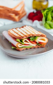 Toast sandwich with gouda cheese and turkey ham filled with tomato and lettuce on a bright background with ingredients in blurry background
