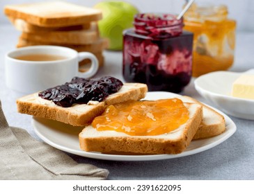 Toast spread with marmalade, butter and two jars of blackberry, raspberry and abicot jam. Horizontal, close. Traditional sweet breakfast. - Powered by Shutterstock