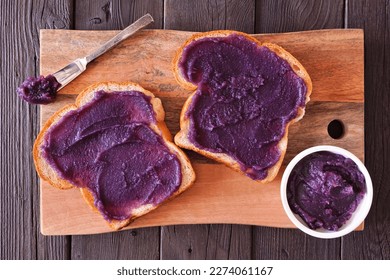 Toast with ube halaya jam. Sweet, trendy, purple yam spread. Above view on a wood serving platter.