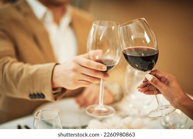 Toast, wine and hands of couple in restaurant for romantic dinner, date and anniversary celebration. Relationship, fine dining and man and woman cheers together for social drinks, alcohol and relax - Powered by Shutterstock