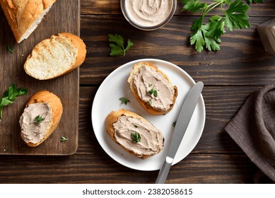 Toasted bread with chicken liver pate on cutting board over wooden background. Top view, flat lay