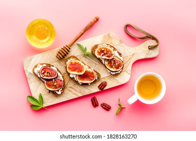 Toasted bread with figs, ricotta and honey on wooden cutting board