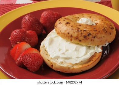 A Toasted Onion Bagel With Cream Cheese And Ripe Strawberries